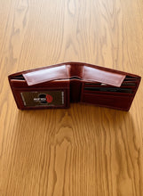 Load image into Gallery viewer, A brown bifold leather wallet with a hidden cash compartment, displayed on a textured surface.